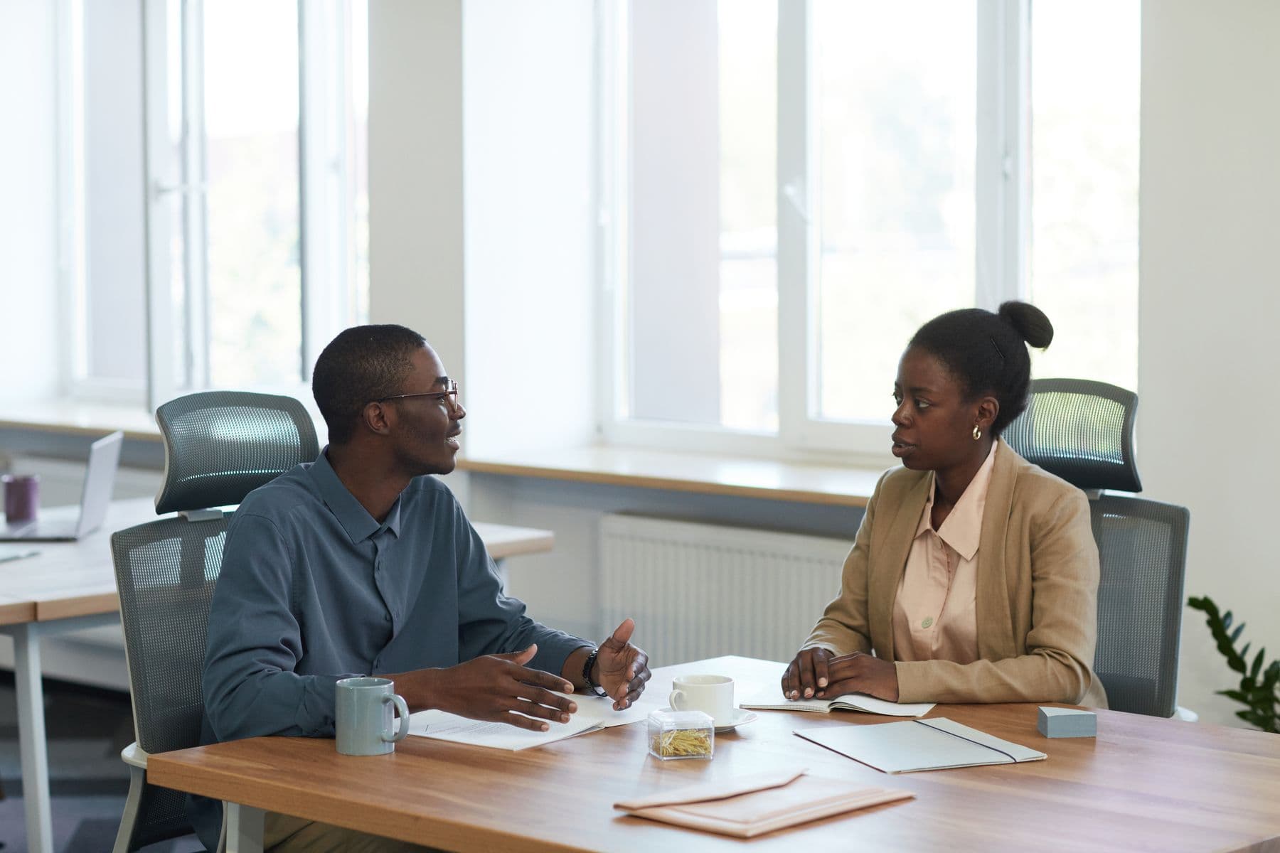 Two people in discussion across a table in an office